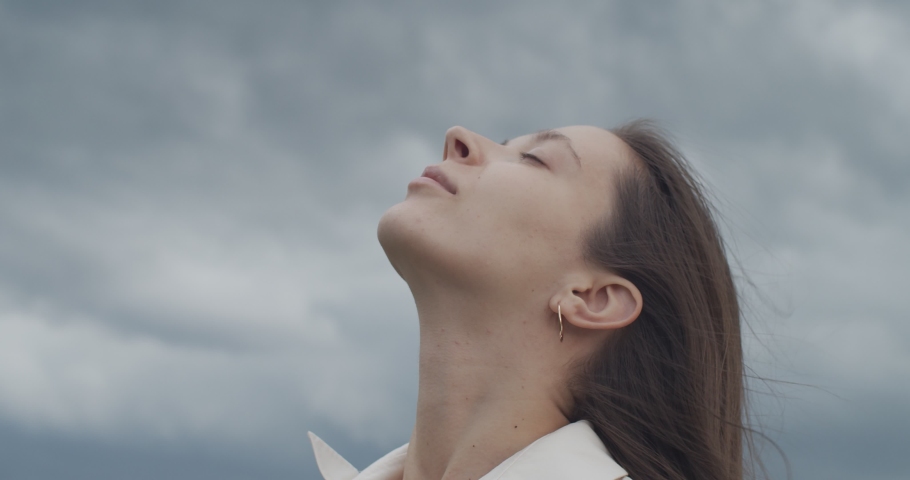 Close up portrait of female face looking up into stormy sky copy text space handheld device. Young woman posing on nature background outdoors slow motion. Trust hope love concept. Facial care Royalty-Free Stock Footage #1058143366