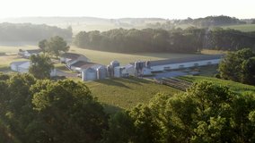 Establishing shot, aerial of family farm in United States, grain bins, chicken house, barn and fields in summer hazy foggy morning light - Powered by Shutterstock - Get 15% off with code: PIKWIZARD15
