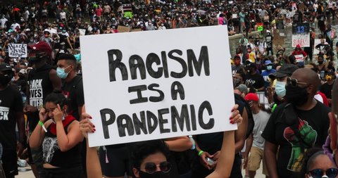 Washington, DC / USA - August 28, 2020:  A woman holds up a sign that says "Racism is a Pandemic".