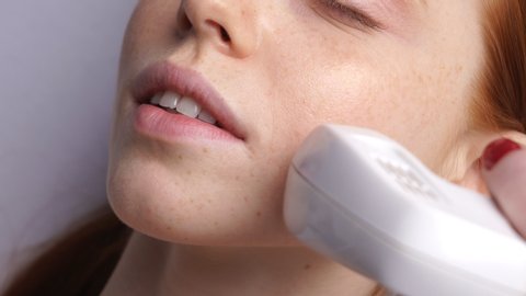 Fractional mesotherapy. A young woman in the office of a cosmetologist receives fractional mesotherapy of the face. Facial skin rejuvenation. Close up.