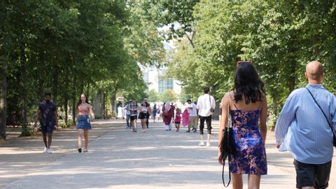 BERLIN, GERMANY - AUG 15, 2020: Many people tourists walk in city center park alley summer time among green trees. This place is between Brandenburg Gate and Reichstag building