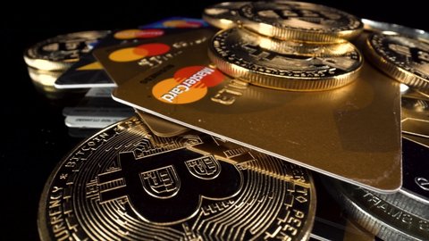 marbella , Málaga / Spain - 08 24 2020: Close up turning Bitcoins BTC and MasterCard credit debit cards on black reflective glass surface, 4k cryptocurrency payments