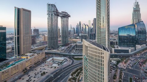 Aerial view of new and tall buildings with busy roads timelapse. Transition from day to night in Dubai Downtown from above, Dubai, United Arab Emirates