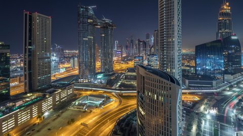 Aerial view of new and tall buildings with busy roads timelapse. Transition from night to day in Dubai Downtown from above with traffic on roads, Dubai, United Arab Emirates