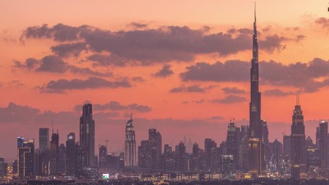 Modern buildings panorama in luxury downtown aerial timelapse of the city after sunset. From day to night transition in financial center Dubai, United Arab Emirates
