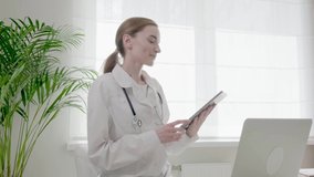 Online doctor's consultation, video communication, application use. Young woman doctor in special clothes, medical gown. 4k video.