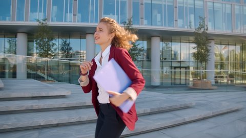 Young business woman looking at watch and running near office building hurry to meeting. Pretty lady in office wear late for work run near business center