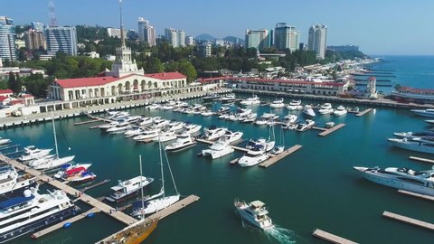 Beautiful summer air flight over the city of Sochi and the sea port. Expensive yachts and boats at the pier. City attraction. Luxury vacation. Panorama of the city on the beach.