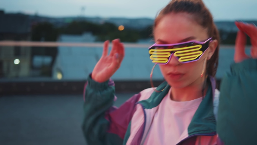Fashion woman with sunglasses and earrings dancing outside looking at camera. Outdoor portrait. Female dancer performing dance show making freestyle stunts. Funny stylish caucasian hipster girl. 4K | Shutterstock HD Video #1058194585