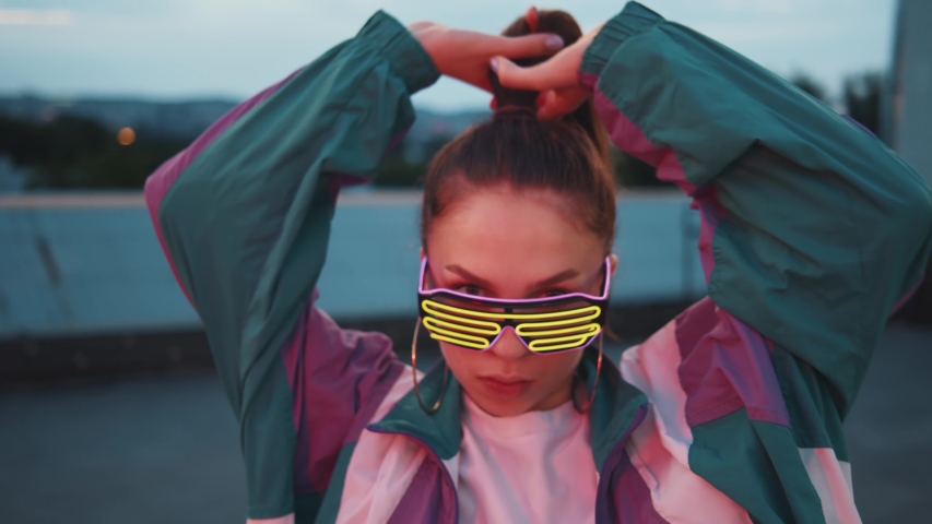 Fashion woman with sunglasses and earrings dancing outside looking at camera. Outdoor portrait. Female dancer performing dance show making freestyle stunts. Funny stylish caucasian hipster girl. 4K | Shutterstock HD Video #1058194585