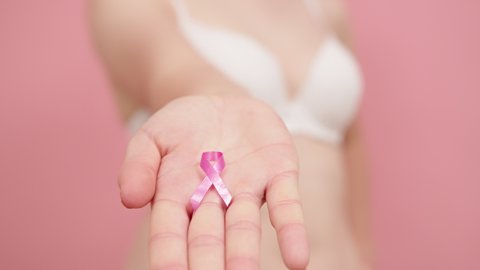 Close up, Woman in bra with pink ribbon in the hand , breast cancer survivor, pink october, awareness month. High quality 4k footage