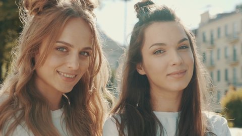 Portrait of two young beautiful smiling hipster girls in trendy summer white t-shirt clothes.Sexy carefree women posing on street background. Positive models having fun and hugging 