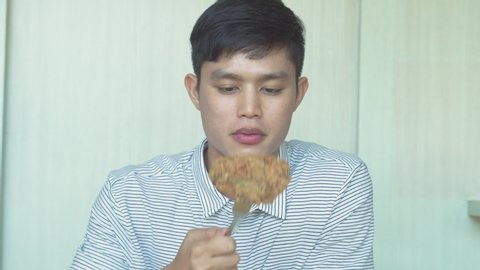 close up shot of young asian  man eating big meal of fried chicken set with happy face at home for brunch meal and enjoy eating concept
