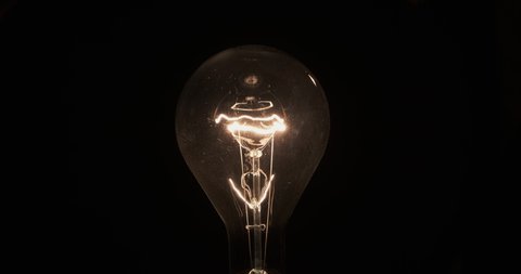 Flashing spiral of an old bulb. Tungsten filament on a black background.