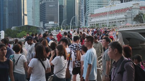 SINGAPORE - JANUARY 10, 2020: Crowd of tourists walking and looking at city from the pedestrian bridge in central business district. Tourism is a major industry and contributor to Singaporean economy