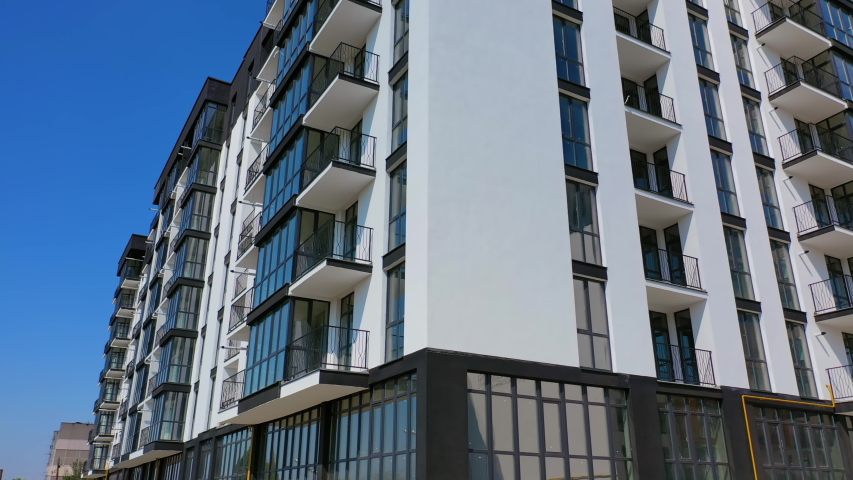Newly built modern apartment building facade. Exterior of multi storey building. Modern design of urban architecture. Aerial view. Motion up.