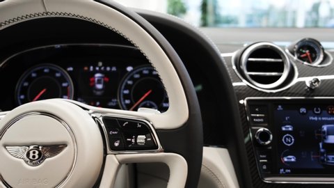 Moscow, Russia - July, 2020: The interior of Bentley Bentayga. in black and white colors. Closeup view on steering wheel and dashboard with speedometer and odometer.