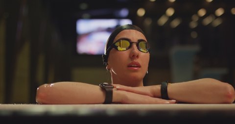 4K View of professional female swimmer in goggles on swimming pool . Exit from swimming pool . Woman swimmer dive in water pool . Girl swimming underwater in the large pool . Close up , slow motion .