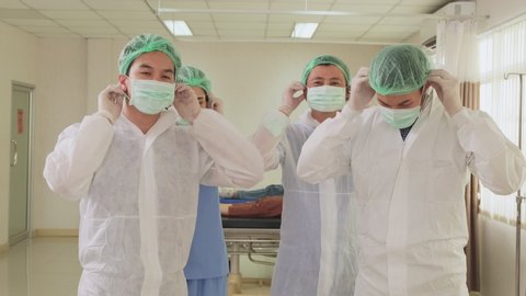 Asian group of doctor put protective surgical mask on to prevent covid virus pandemic. Portrait of medical people in doctor gown wearing mask in hospital. New normal lifestyle in health occupation.