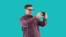 A man dressed in a plaid shirt takes video on a smartphone.