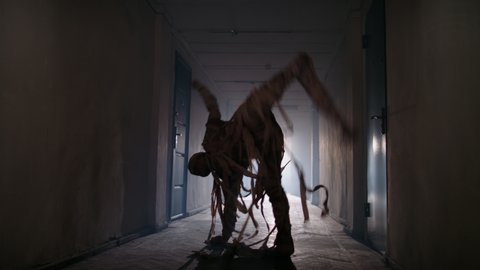Guy in thematic bandaged costume of halloween mummy doing a cool breakdance in hallway of haunted house, representing halloween in funny way 4k footage Stock-video