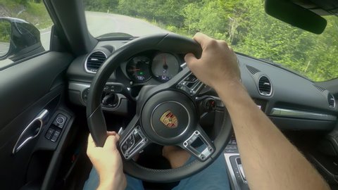 LJUBLJANA, SLOVENIA, MAY 2020, POV: POV: Driving down empty country road winding through the forest in a new Porsche. Scenic drive through the woods in a supercharged Porsche. Joyride in a supercar.