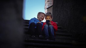 Two brothers play computer games. Friends play mobile games on smartphones while sitting on the stairs. Best friends met in the evening. Cybersport. Online education. - Powered by Shutterstock - Get 15% off with code: PIKWIZARD15