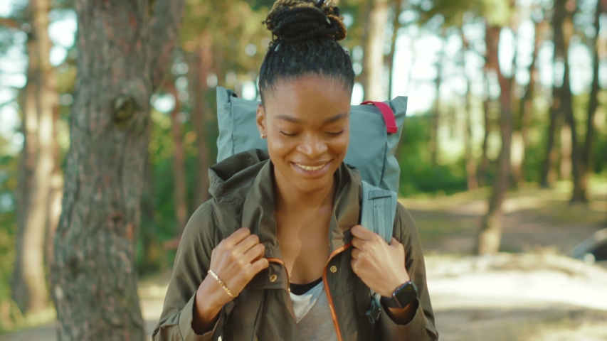 Euphoric pretty woman with tourist backpack walking alone through summer forest wild nature enjoying african safari hiking adventure alone. Portraits. Royalty-Free Stock Footage #1058231848