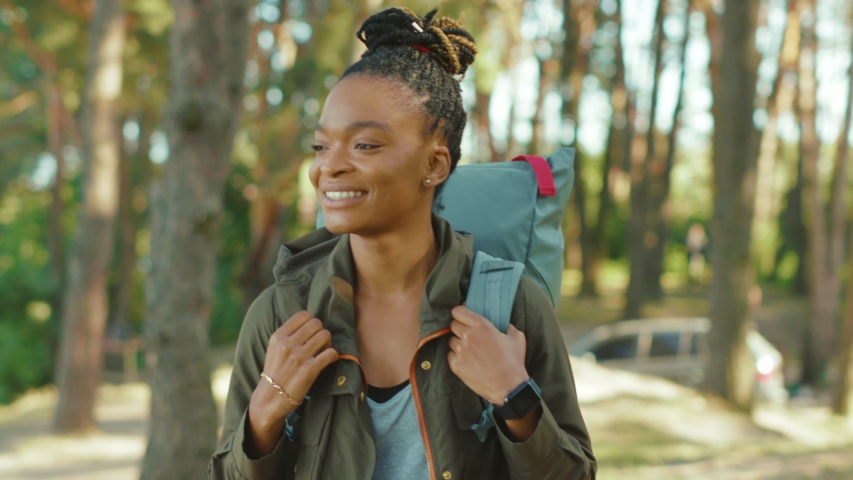 Euphoric pretty woman with tourist backpack walking alone through summer forest wild nature enjoying african safari hiking adventure alone. Portraits. Royalty-Free Stock Footage #1058231848