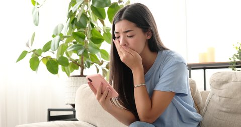Woman upset on reading bad news using mobile phone at home