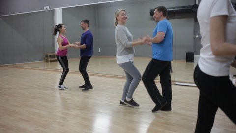 Cheerful adults learning to dance kizomba with partners in dancing group class