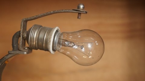 Taking incandescent light bulb from lamp socket slow motion video