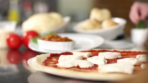 A chef adds toppings to a homemade pizza.