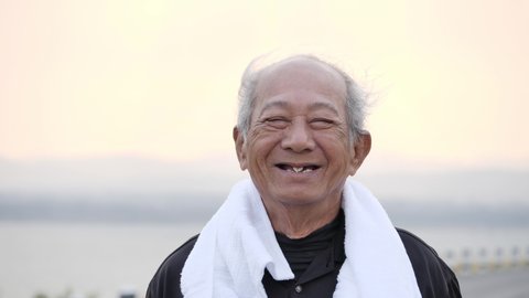 Front view Asian elderly exercise happy smile, laugh, Positive Emotion. Close up Senior man on road in the morning sunshine. health lifestyle and exercise Concept.