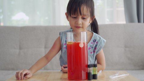 A 5 years old asian schoolgirl is make easy science experiment at home about carbon dioxide release from effervescent tablet in the liquid layer of water and oil, concept of learning activity for kid.