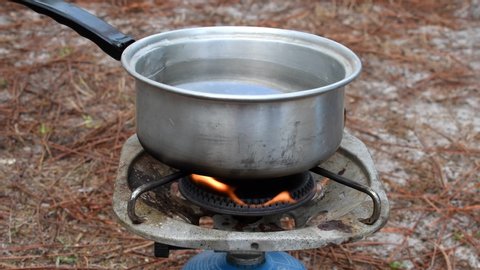 saucepan with water heated on a gas stove when camping: boiling water for cooking food in a container on a portable gas heater