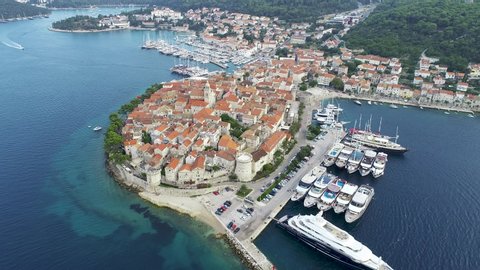 Aerial view of famous Croatian island Korcula, with mediterranean architecture, marina and luxury yachts and sailboats embarked. Warm, sunny summer day in Dalmatian city. Vacations in Croatia.