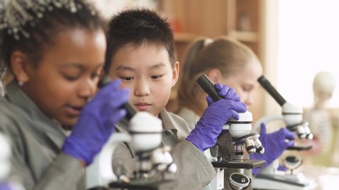 Lesson in a modern school. kids look at microscopes in a chemistry lesson, the process of teaching children in a modern school.
