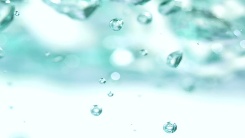 Slow motion and super macro shot of side view of surface level of green hued boiling water with bubbles in selected focus on white background Royalty-Free Stock Footage #1058250121
