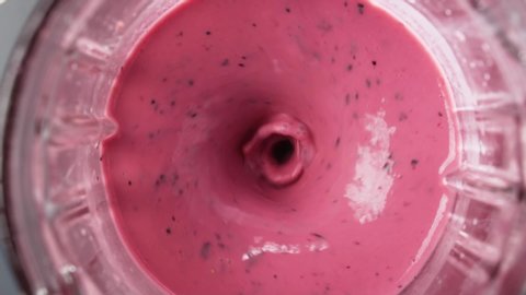 Red berry smoothie blended in blender, top view, slow motion. Healthy eating concept.