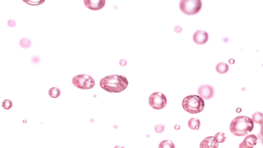 Close up of pink hued micro air bubbles flowing up and down under water over a white background Royalty-Free Stock Footage #1058250340