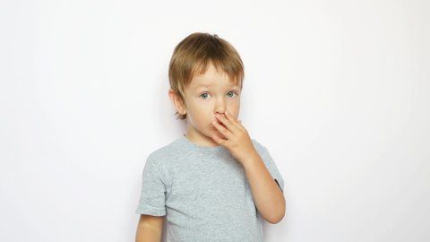 One lovely little boy picking his nose against white background