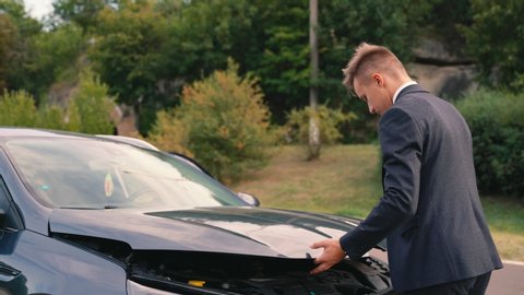man opens the hood of the car. rear view of a man examine broken car in outdoor. The car broke down on the road. Unforeseen situation.