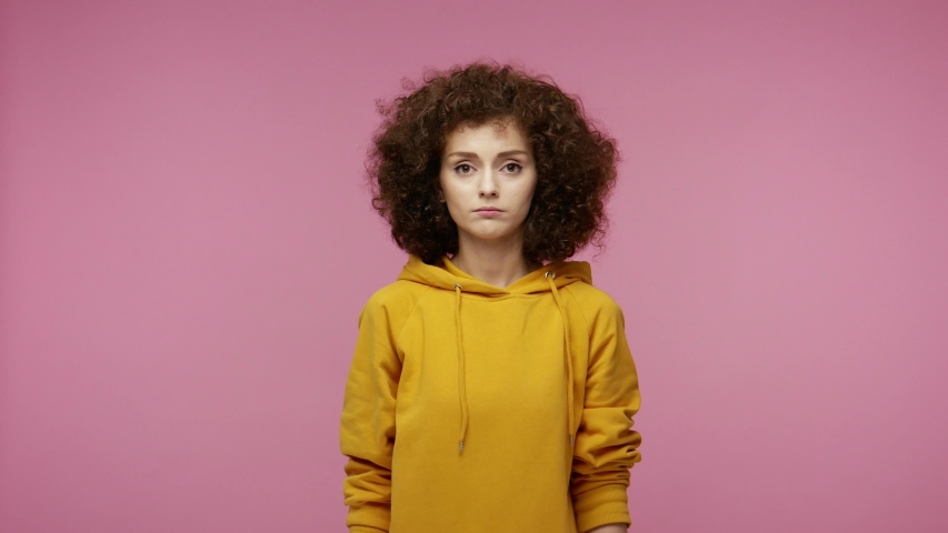 Please, I'm begging! Upset young woman afro hairstyle in hoodie appealing to camera with pleading imploring eyes, keeping prayer gesture and asking help. indoor studio shot isolated on pink background Royalty-Free Stock Footage #1058259343