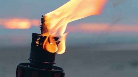 Tropical Bamboo Torch Burning in the Beach at Summer Evening. Decorative Candle Has a Massive Orange Flame Using Oil Fuel or Kerosene - Slow Motion. CloseUp Static Shot