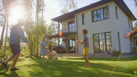 Beautiful Family of Four Play Catch Toy Ball with Happy Golden Retriever Dog on the Backyard Lawn. Idyllic Family Has Fun with Loyal Pedigree Dog Outdoors in Summer House Backyard.Handheld Dolly Shot