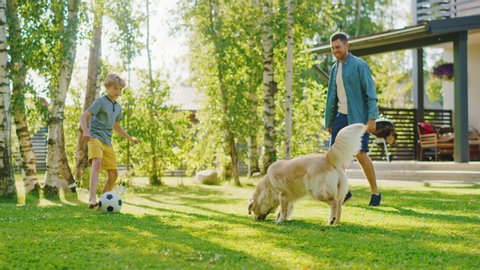 Handsome Father and Son Spend Quality Family Time Together, Play Soccer with Football, Passing to Each other, and Having Fun. Sunny Day Idyllic Suburban Home Backyard with Loyal Golden Retriever Dog