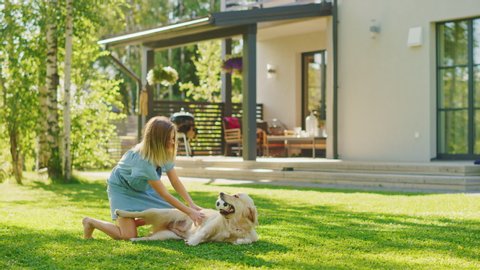 Cute Girl Has fun with Happy Golden Retriever Dog on the Backyard Lawn. She Pets, Play, Tackle it on the Ground And Scratches Stomach. Pedigree Dog Holds Toy Football in Jaws. Idyllic Summer House