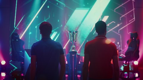 Two Professional eSports Gamers walking on Stage to Participate in the Cyber Games Championship Event. Competitive Online Live Streaming Tournament. Stylish Following Back View Shot