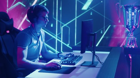 Two Professional Esport Gamers Compete in a Video Game Playing on a Championship Event and Stylish Neon Arena. Online Streaming Cyber Gaming Tournament. Zoom in Descending Crane Portrait Camera Shot